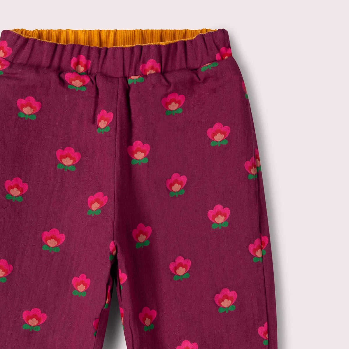 Close-up of the elastic waistband and pink flower print on purple reversible trousers.