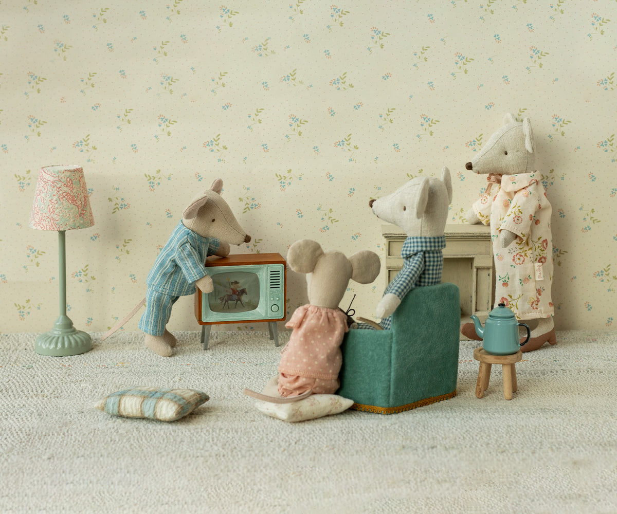 Miniature scene with toy animals in a living room setting, including a television, a mouse on a couch and another on a chair.