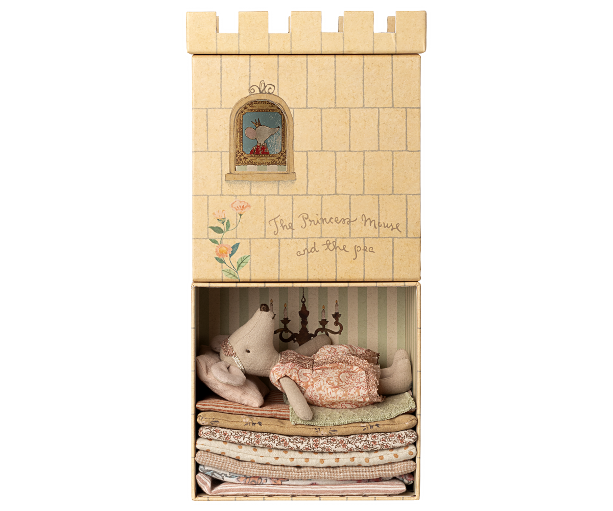 Wooden toy castle with stuffed animals and bedding inside on a white background