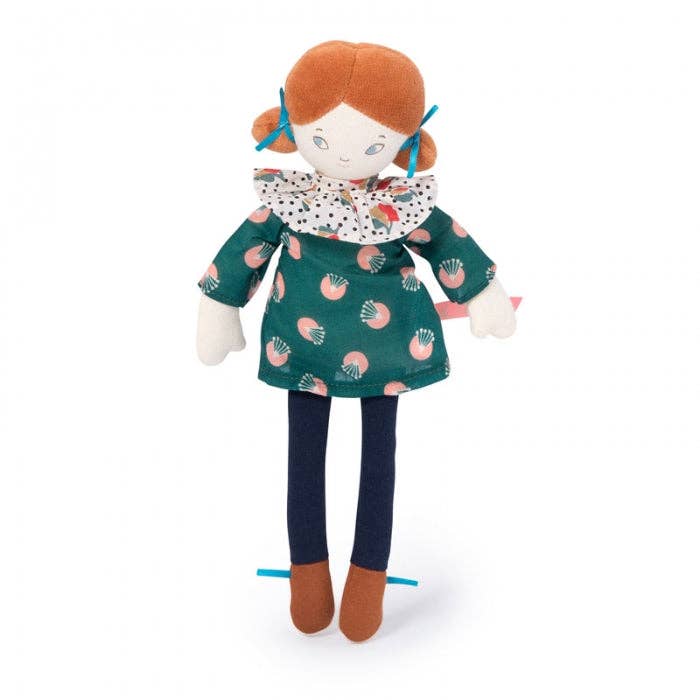 A plush doll named Mademoiselle Blanche from the Parisiennes collection, wearing a green patterned dress and navy leggings, with two blue ribbons in her hair.