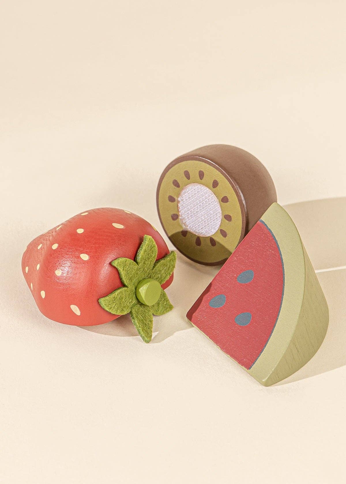 wooden kiwi, strawberry, and watermelon toys on a white background