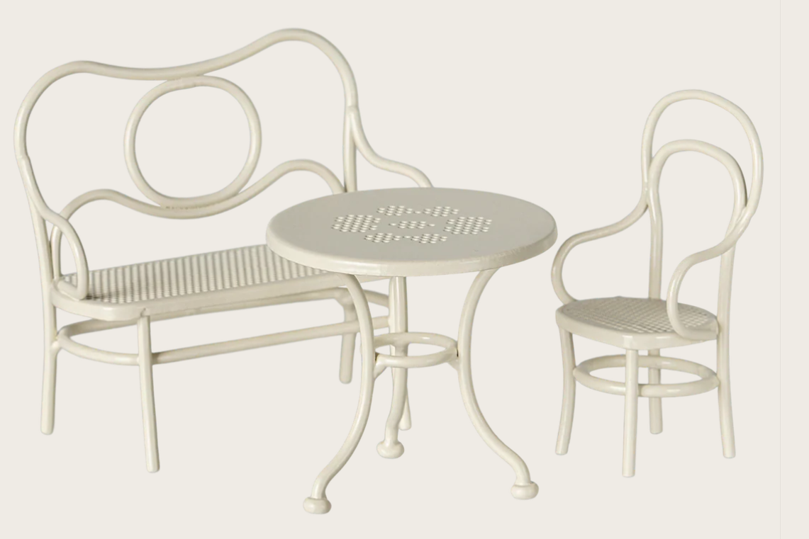 White metal outdoor furniture set with bench, table, and chair on a light gray background
