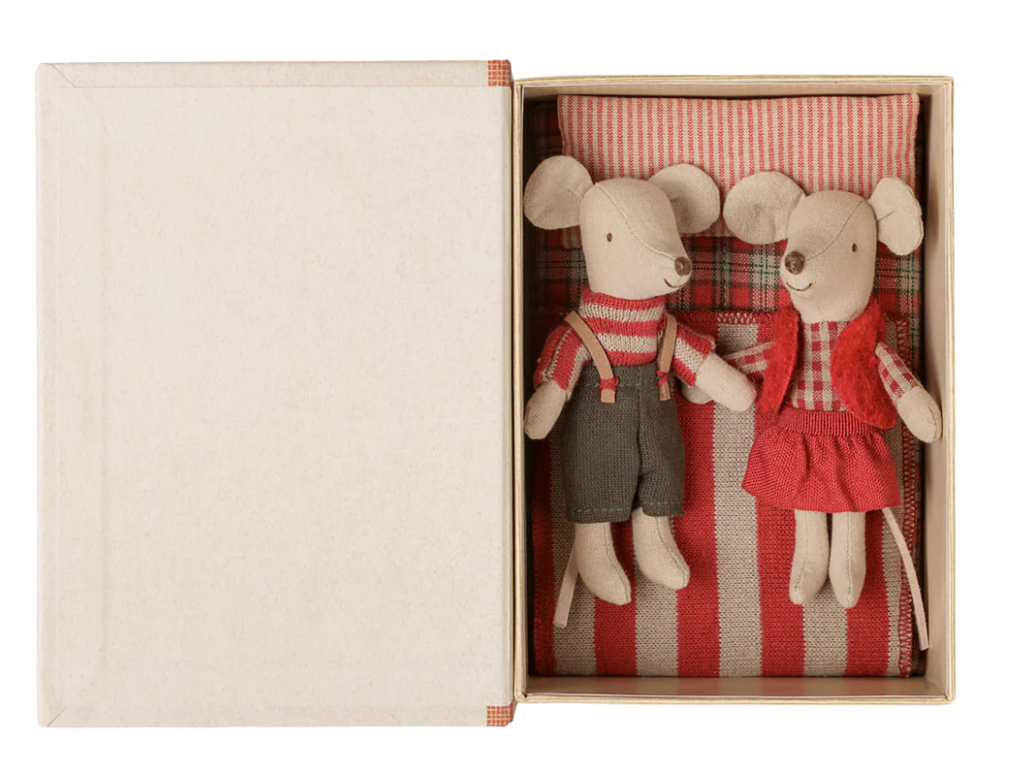 Maileg Christmas twin mice wearing red gingham and striped outfits laying in bed inside faux book on white background