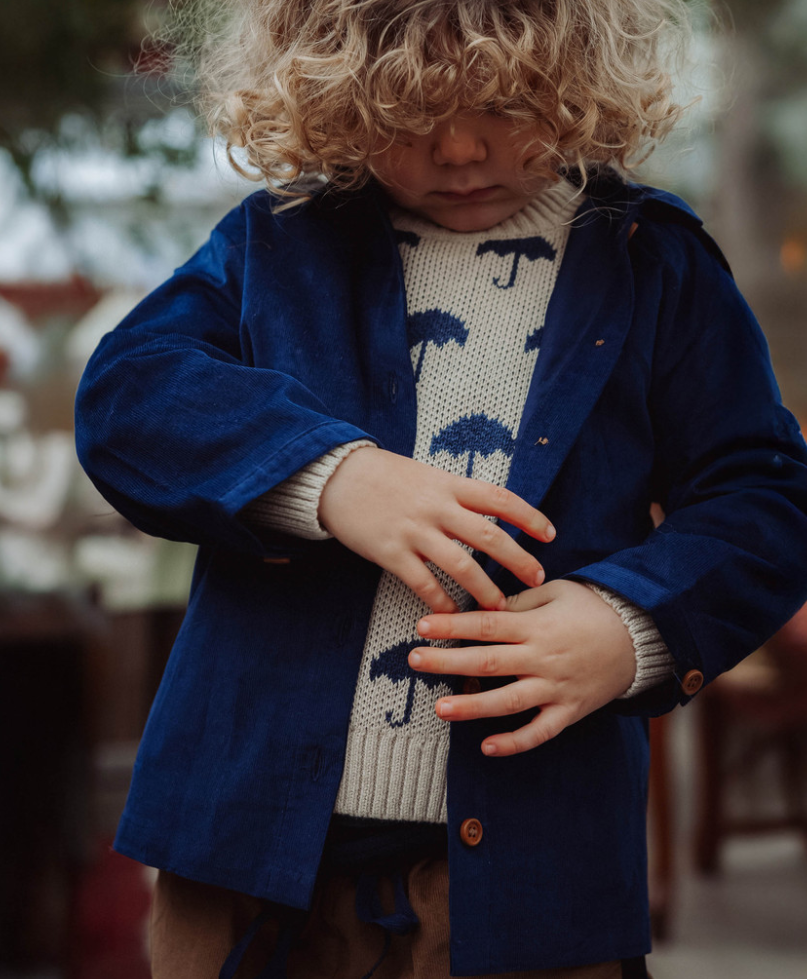 Child wearing blue button down shirt over a sweater with umbrella design on it