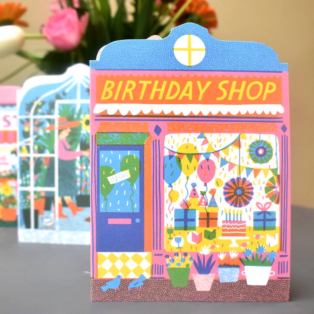 Card on a table with illustration of a shop front with the text Birthday Shop