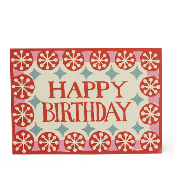A greeting card with 'Happy Birthday' text in red and a pattern of small white and pale turquoise circles on a coral background.