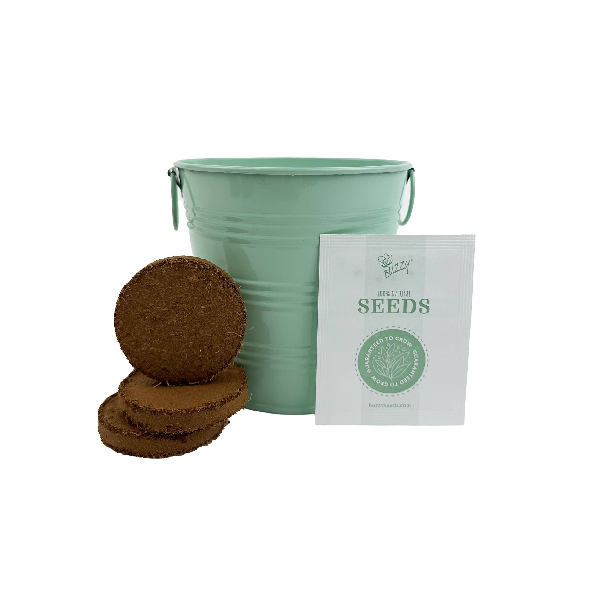 Green metal bucket, brown growing medium pellets and a white seed packet on a white background