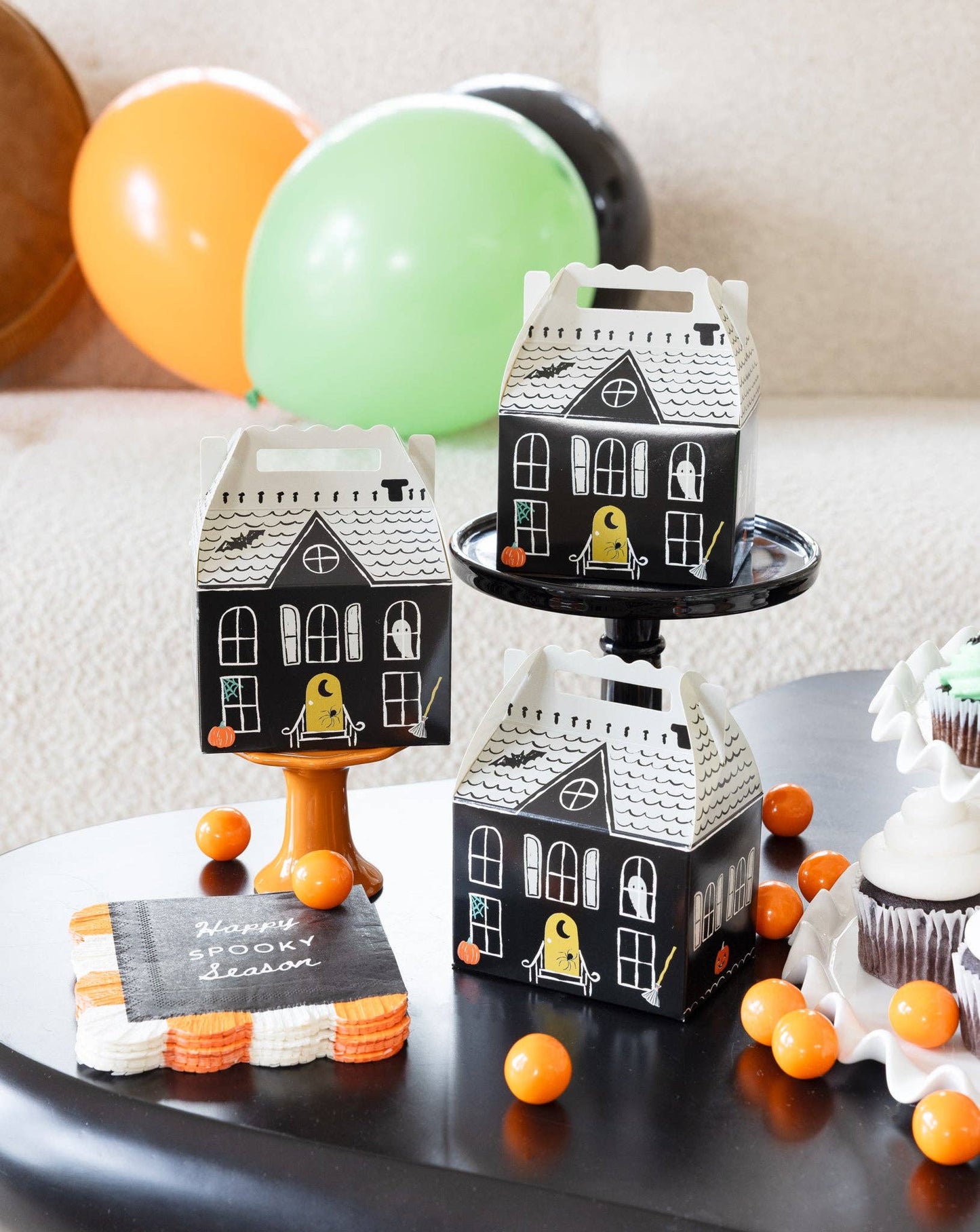 Halloween-themed house-shaped boxes with decorative elements on a table.