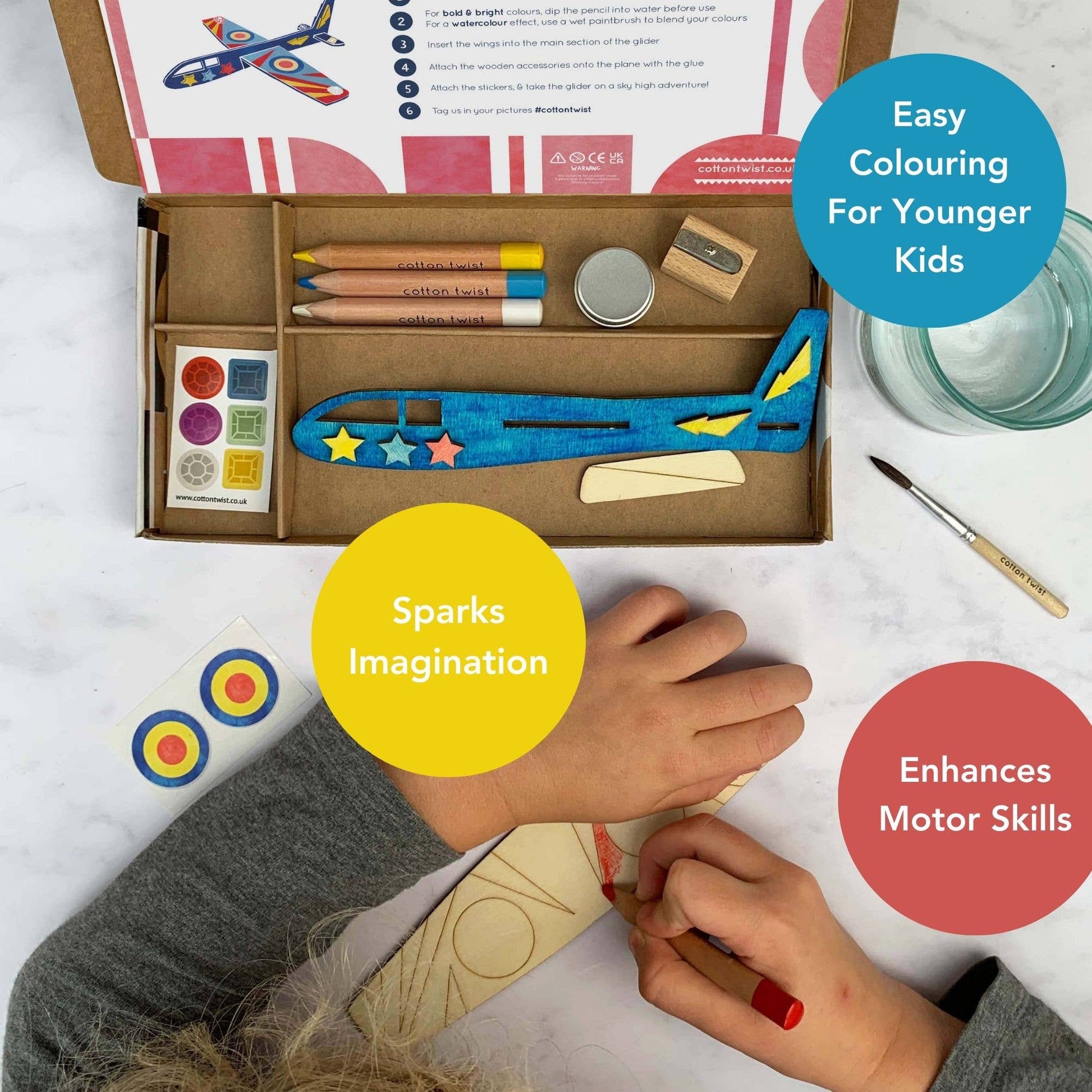 Children's craft kit with instructions, colored pencils, and airplane model on a white surface. "Sparks imagination, Easy Coloring for Younger Kids, Enhances Motor Skills"