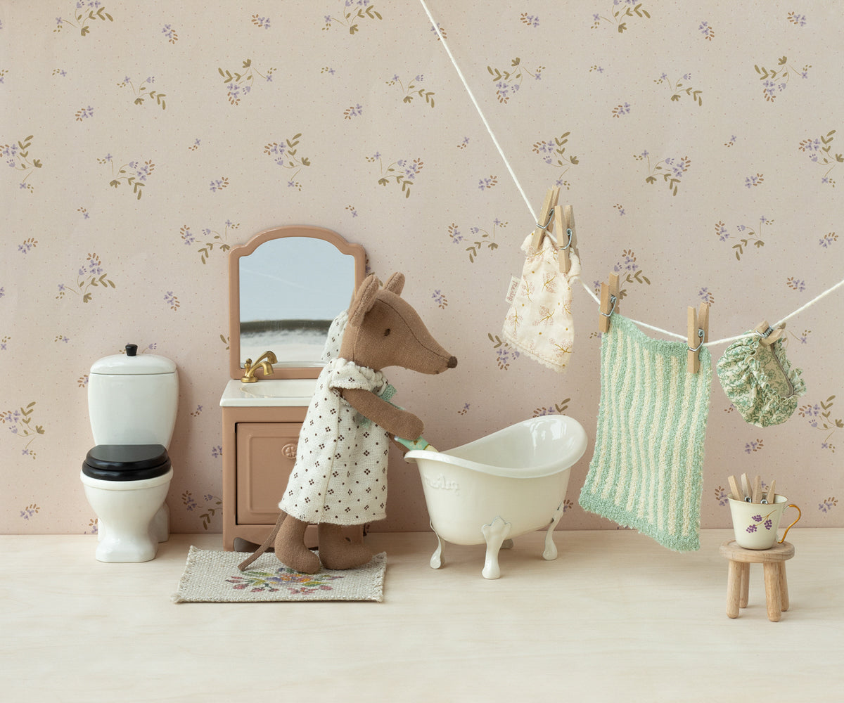 Miniature bathroom scene with a mouse character in a bathrobe, bathtub, and floral wallpaper.