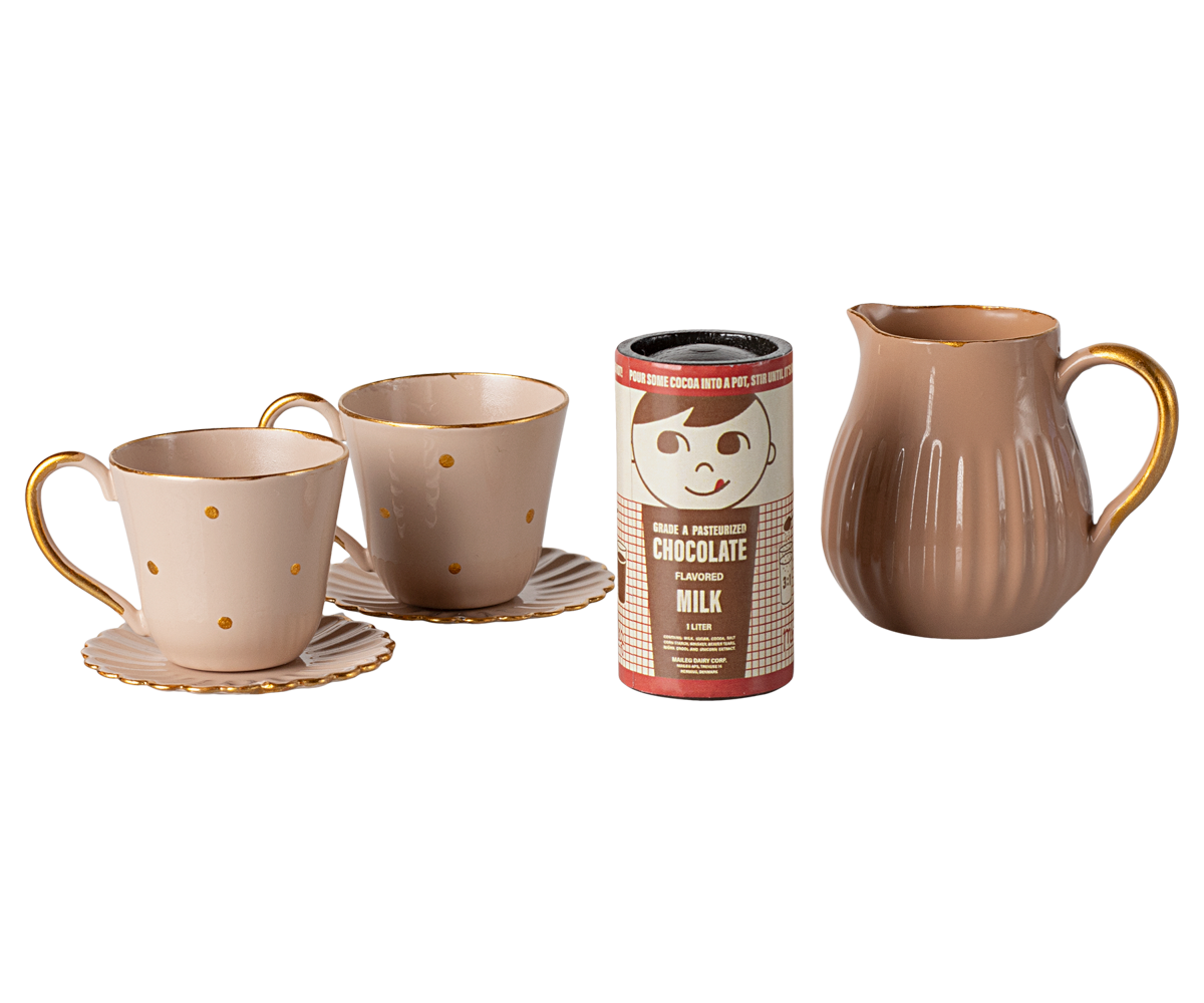 Ceramic mugs, a pitcher, and a hot chocolate canister on a white background
