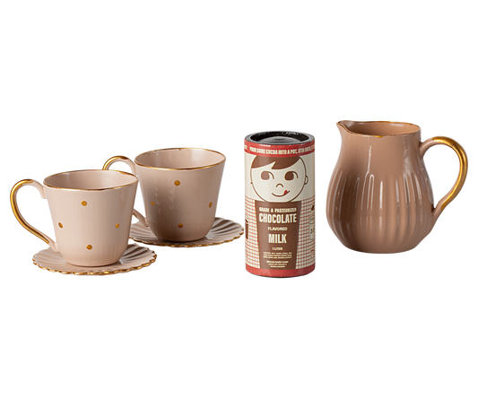 Ceramic mugs, a pitcher, and a hot chocolate canister on a white background