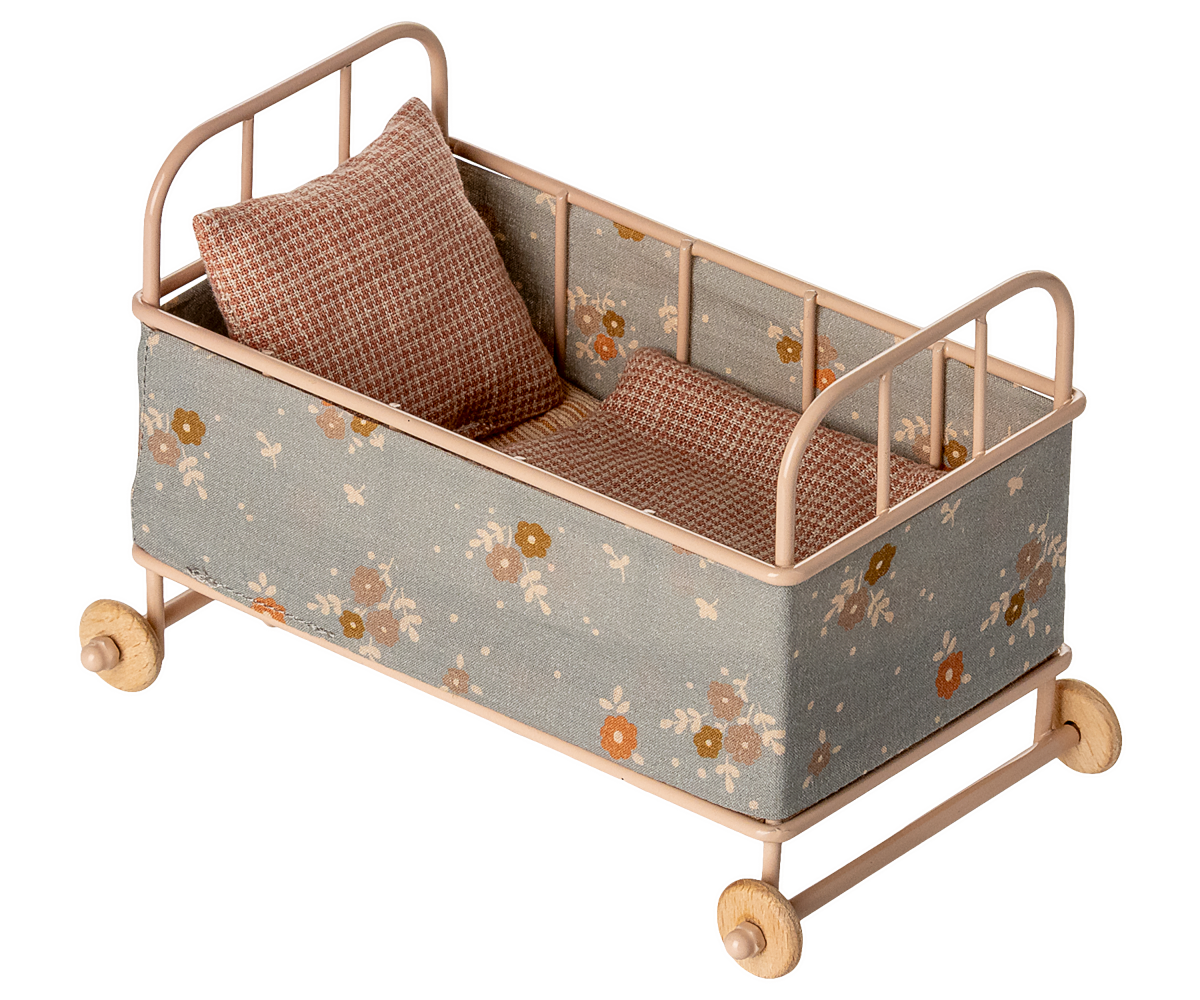 Small decorative bed with floral pattern and wheels on a white background