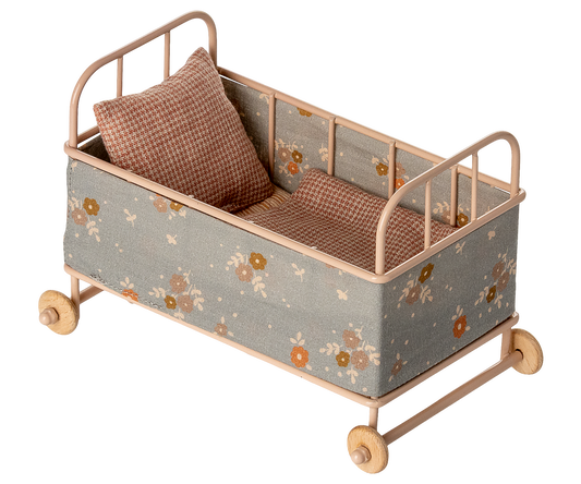 Small decorative bed with floral pattern and wheels on a white background