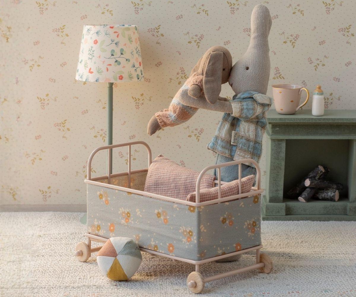 Miniature children's room with a toy rabbit in a small bed, lamp, and toys on a shelf.
