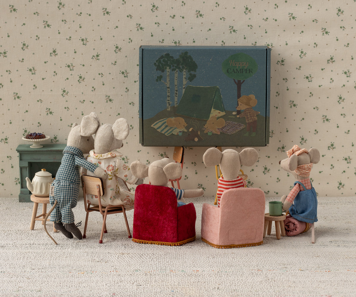 Miniature scene of mice watching a movie on a screen with a floral wallpaper background.