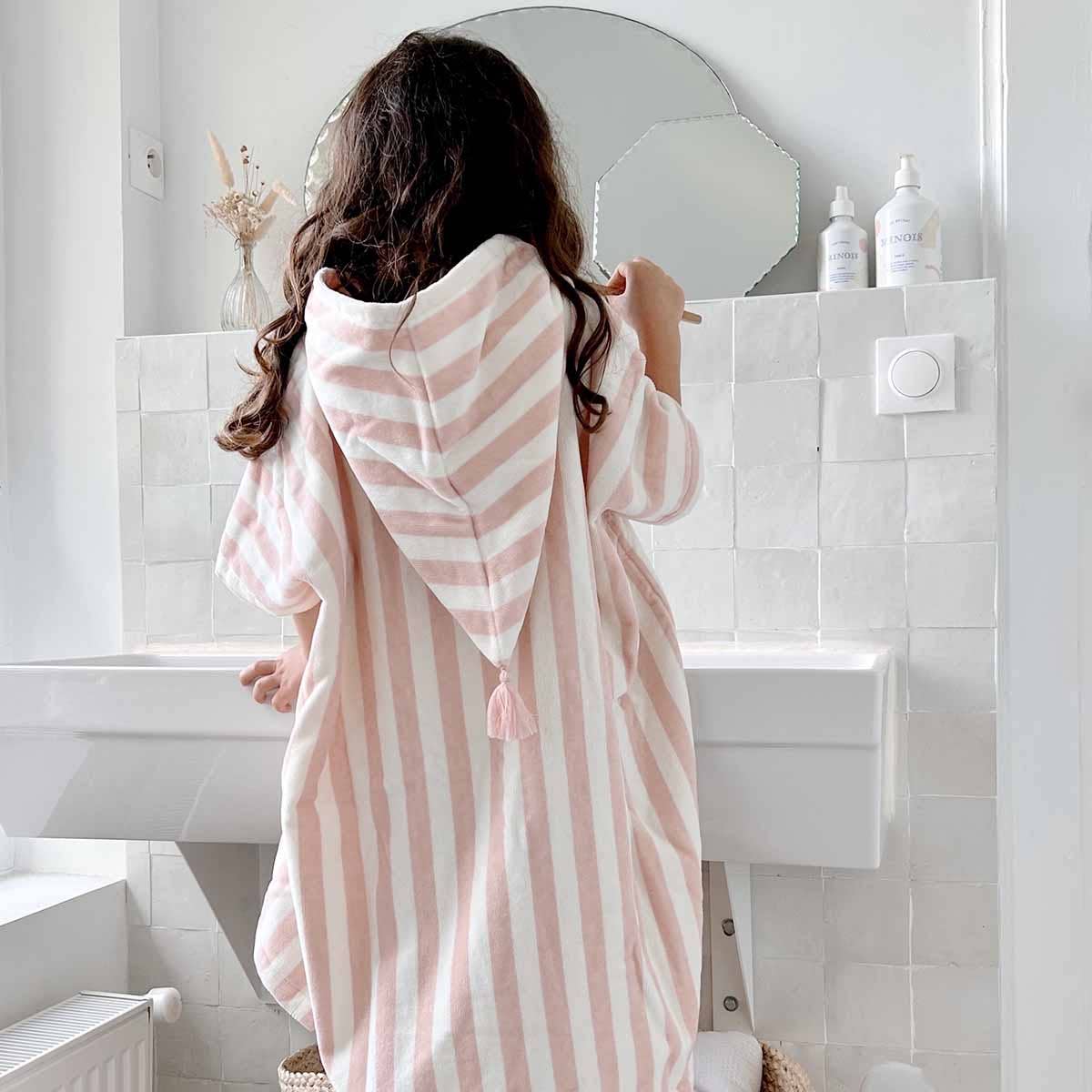 Person wrapped in a pink and white striped towel in a bathroom.