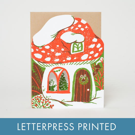 A holiday greeting card in the cutout shape of a mushroom, featuring a little mouse family trimming the tree printed inside! Letterpress printed and packaged with a kraft paper envelope. 