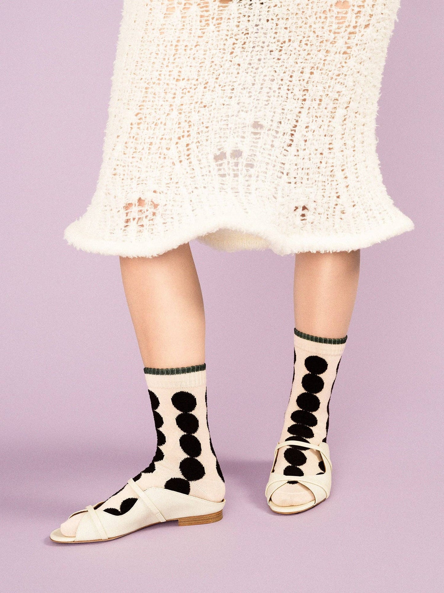 Person wearing polka dot socks with a light purple background