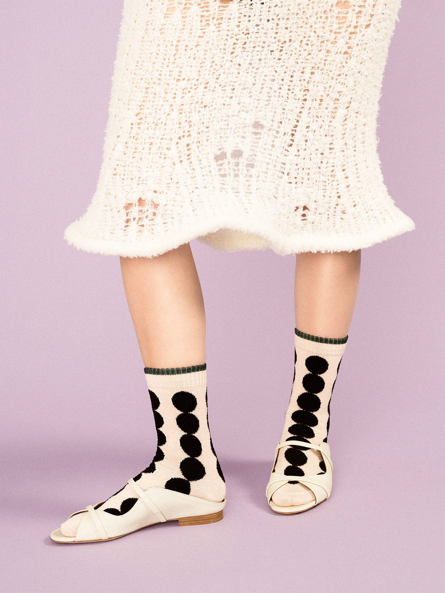 Person wearing polka dot socks with a light purple background