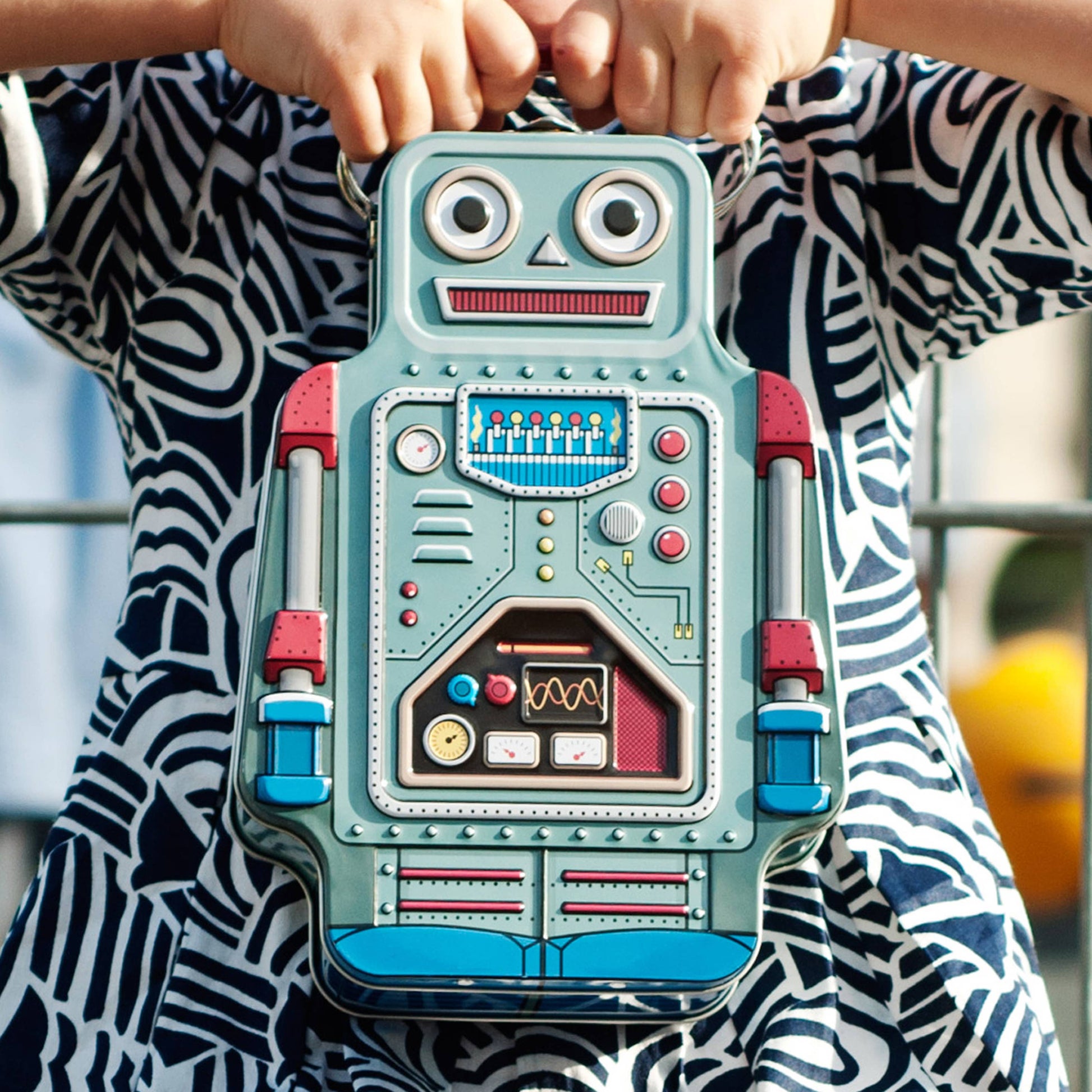 child wearing a black and white dress holding a robot metal lunchbox