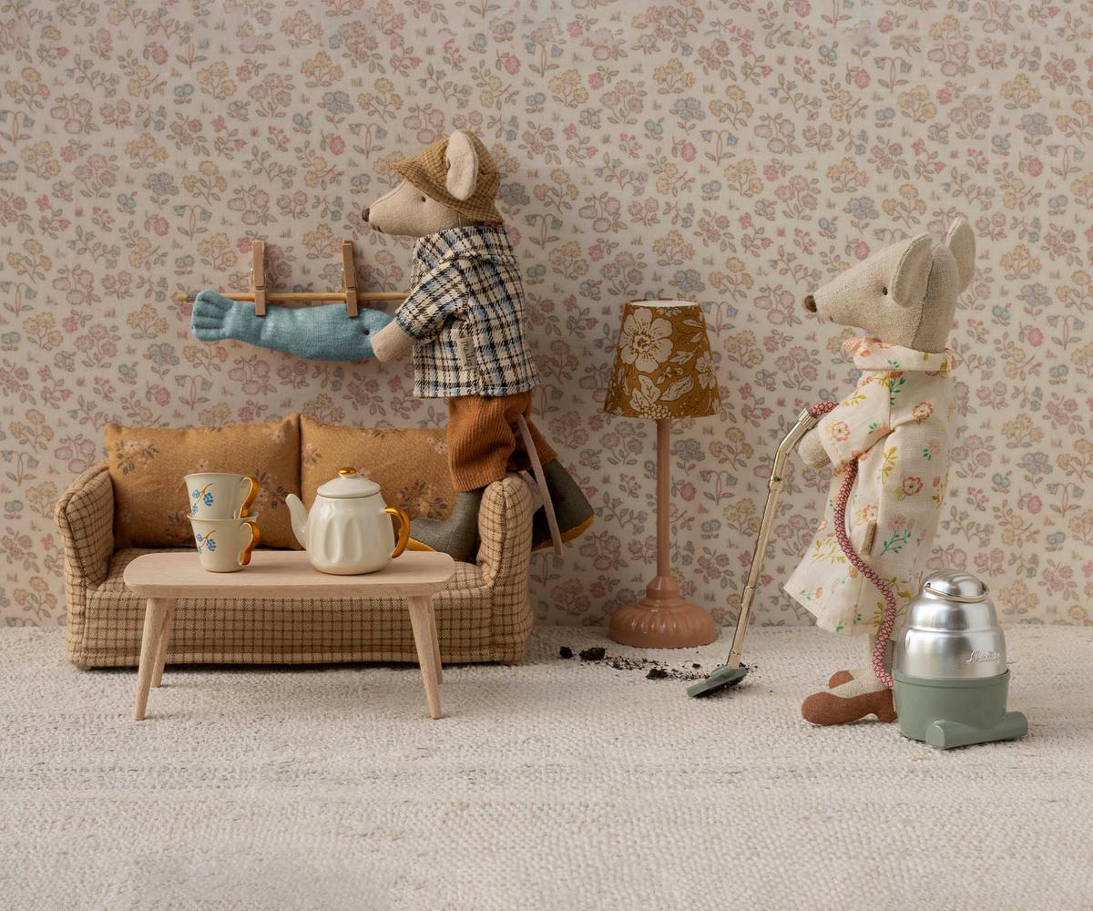 Two toy mice in a room with furniture and decor, including a lamp and a teapot.