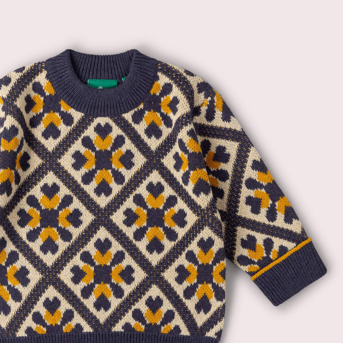 Close-up of the ribbed neckline and diamond pattern on a navy, cream and mustard jumper.