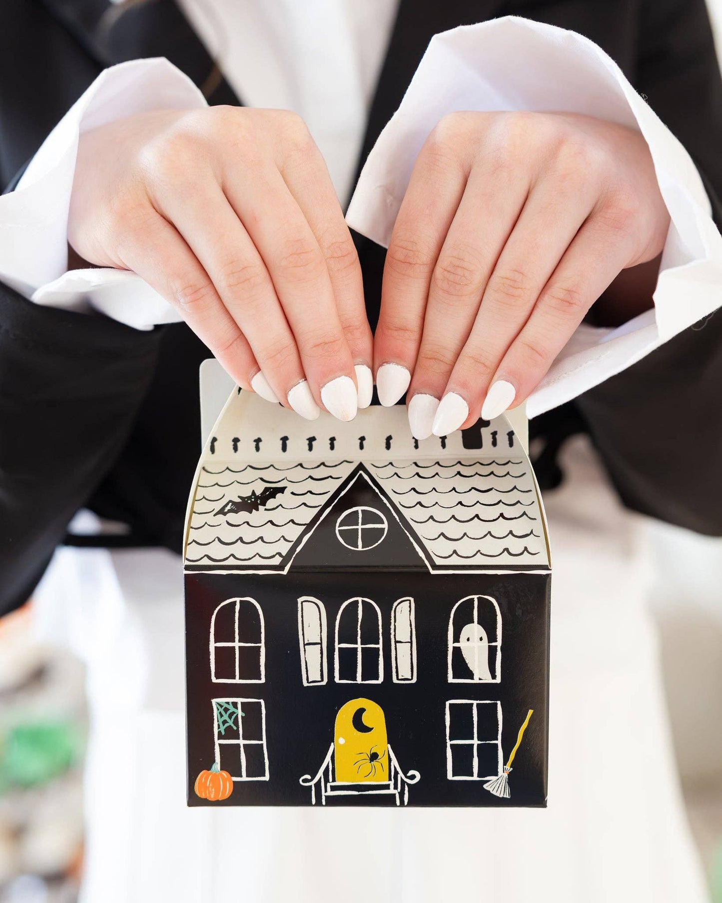 Halloween-themed treat box held by a person with white nail polish.