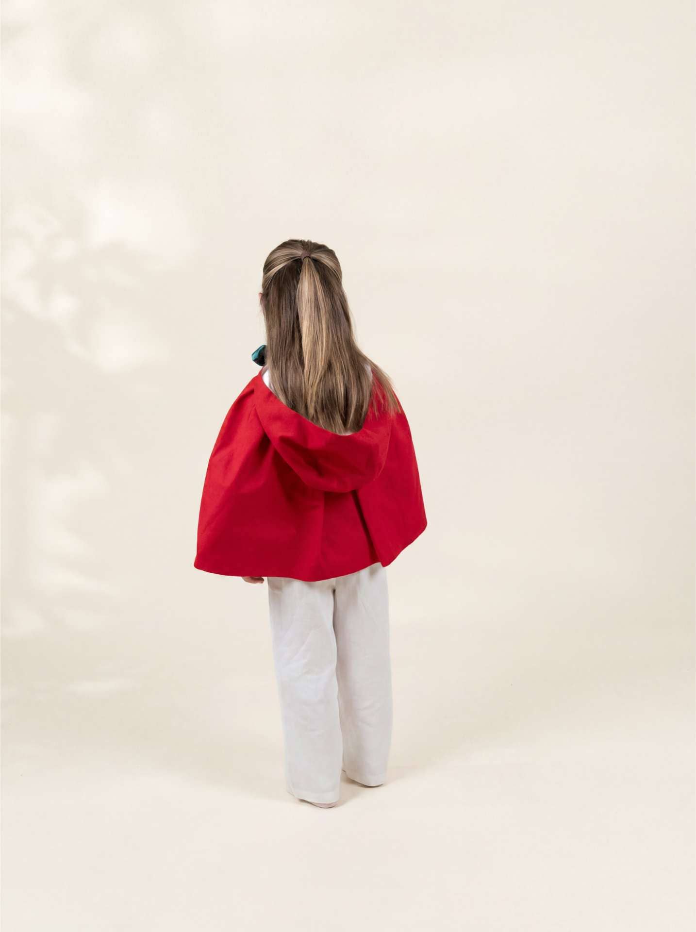 Person wearing a red cape on a plain background