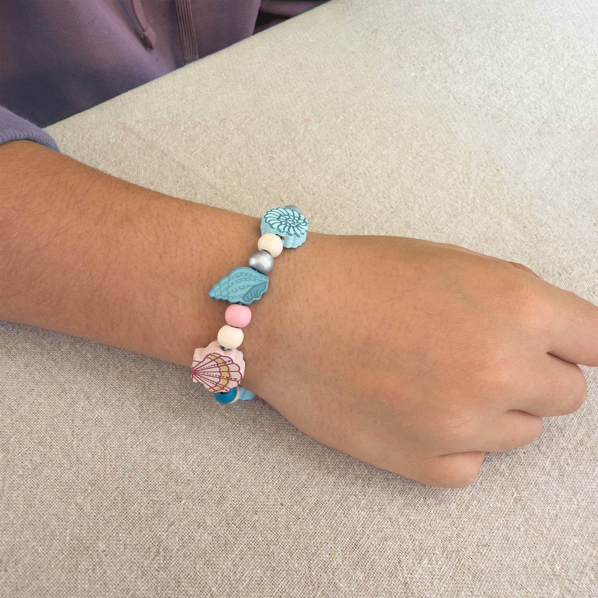 Bracelet with colorful beads on a wrist against a neutral background