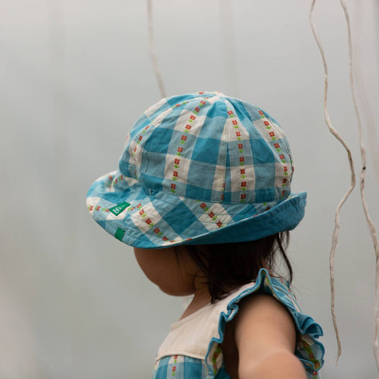 Child wearing a blue checkered hat against a plain background