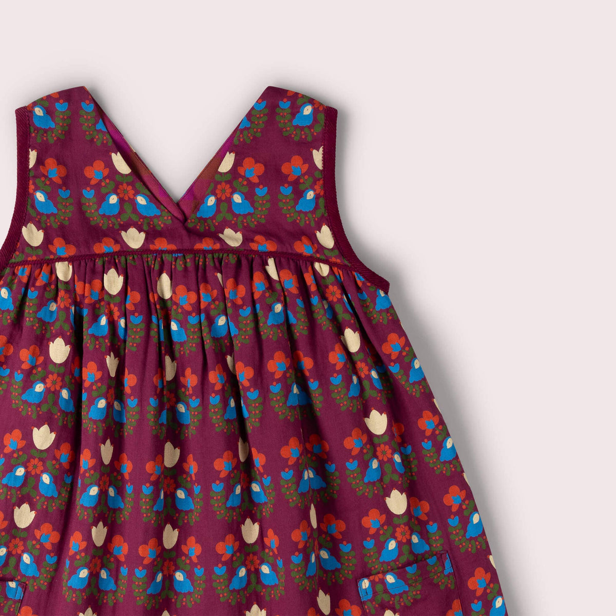 Close-up of the V-neckline and blue bird and flower print on a burgundy swing dress.