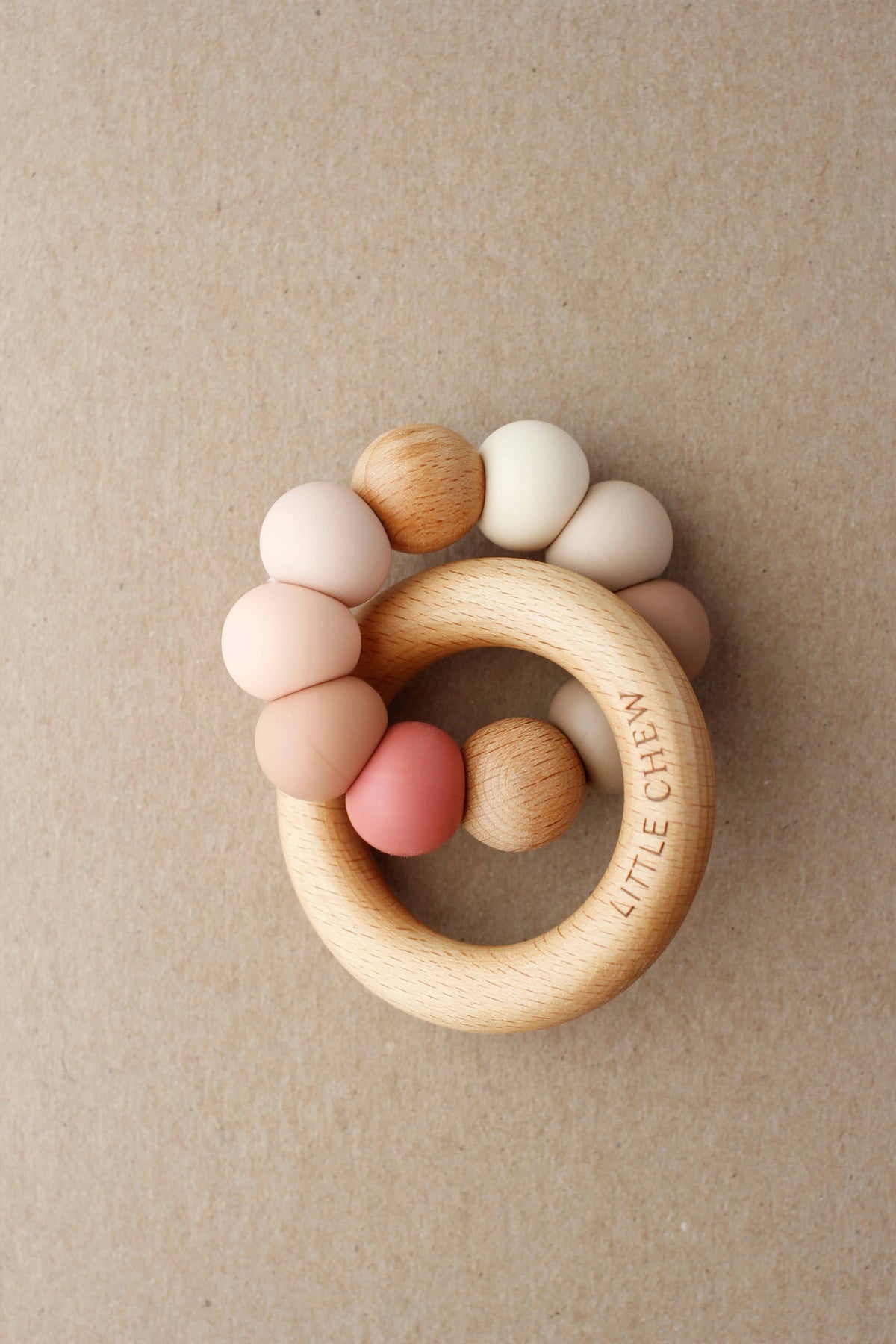 Wooden teething ring with colorful beads on a beige background