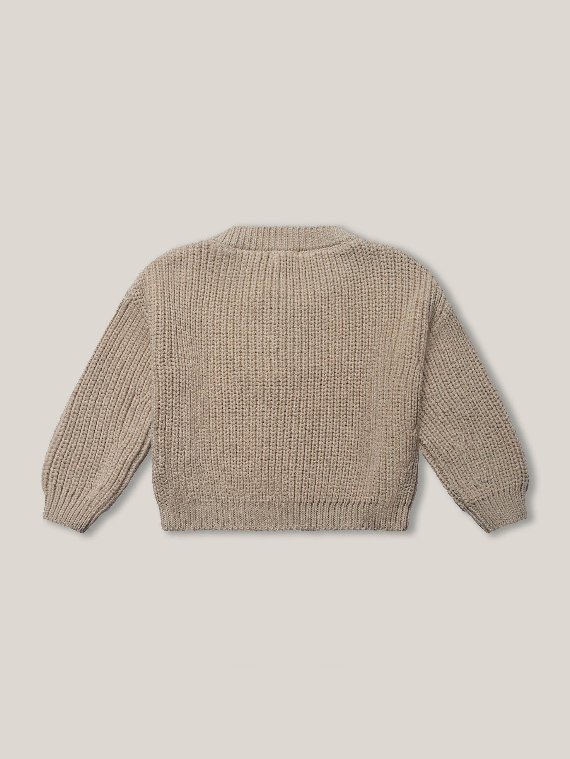 Back view of beige knitted sweater on a light beige background
