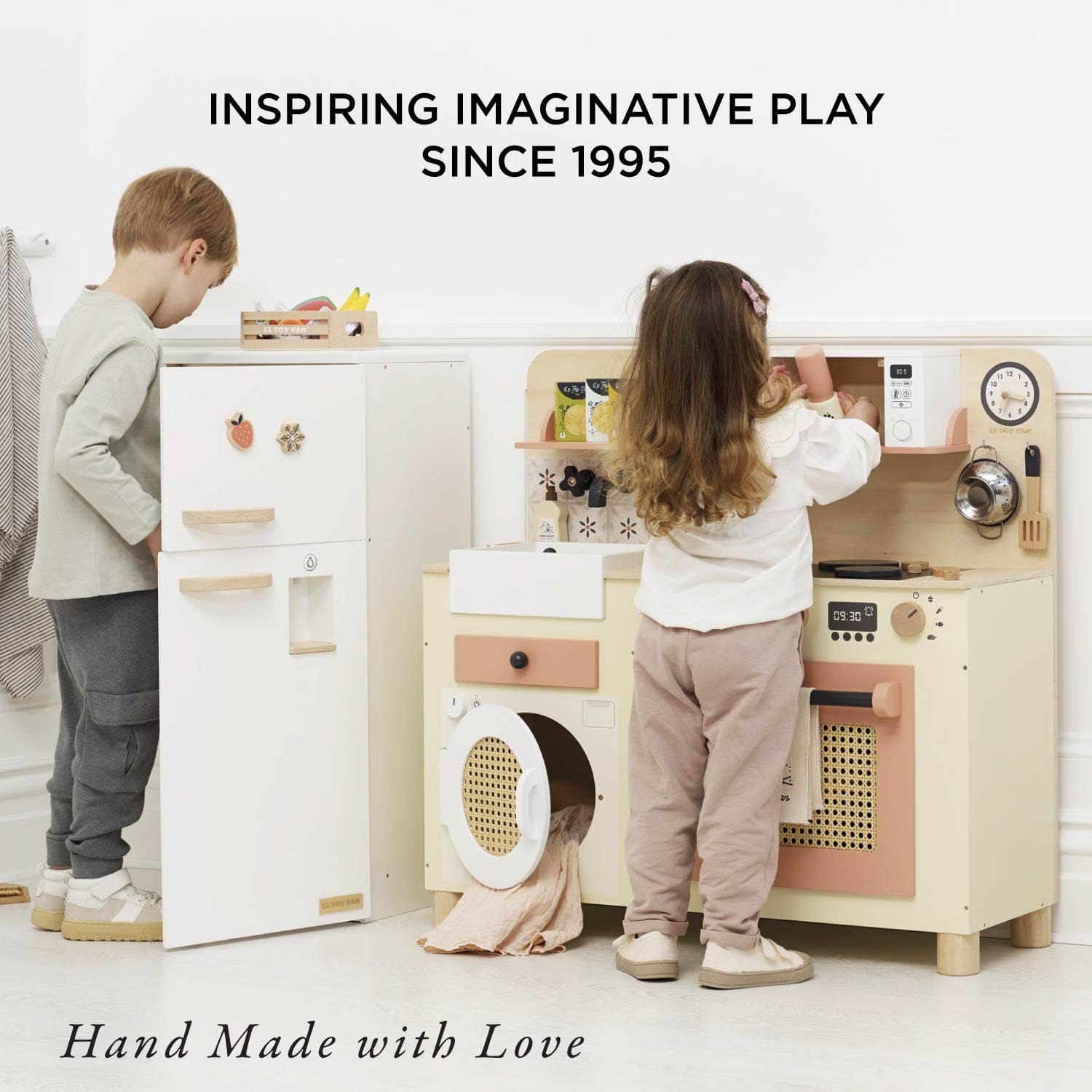 Children playing with a wooden play kitchen set in a room.