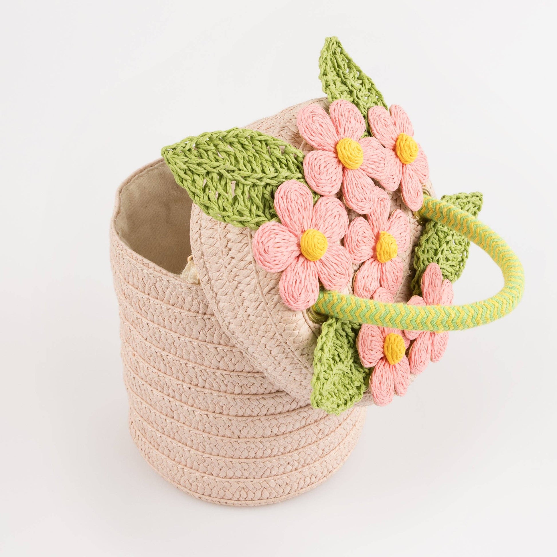 Crocheted basket with pink flowers and green leaves on a white background