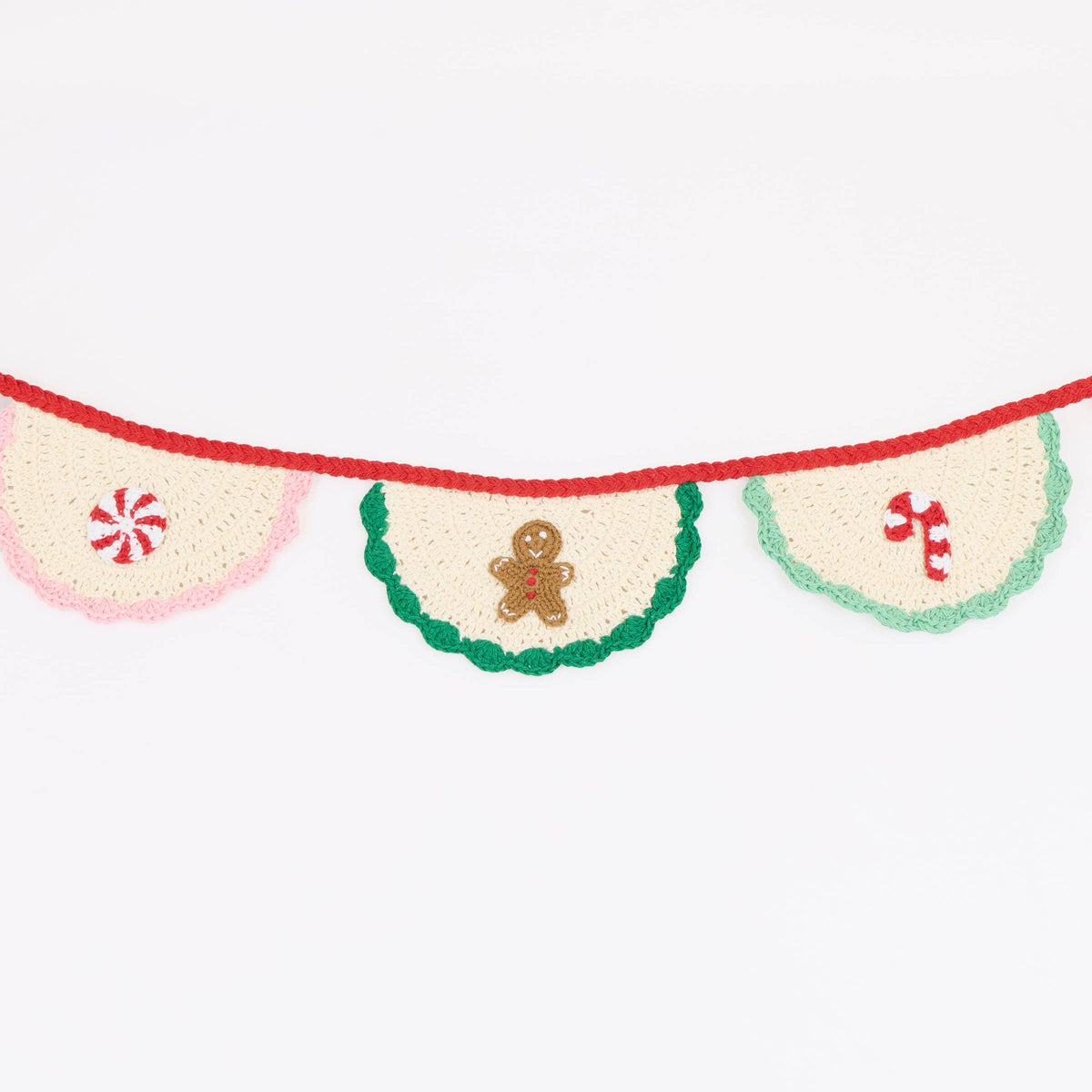 A festive crocheted banner garland with three cream-colored fan-shaped pennants. The center pennant is decorated with a green crocheted border and a small gingerbread man figure, while the side pennants are pink and mint green with red candy cane motifs.