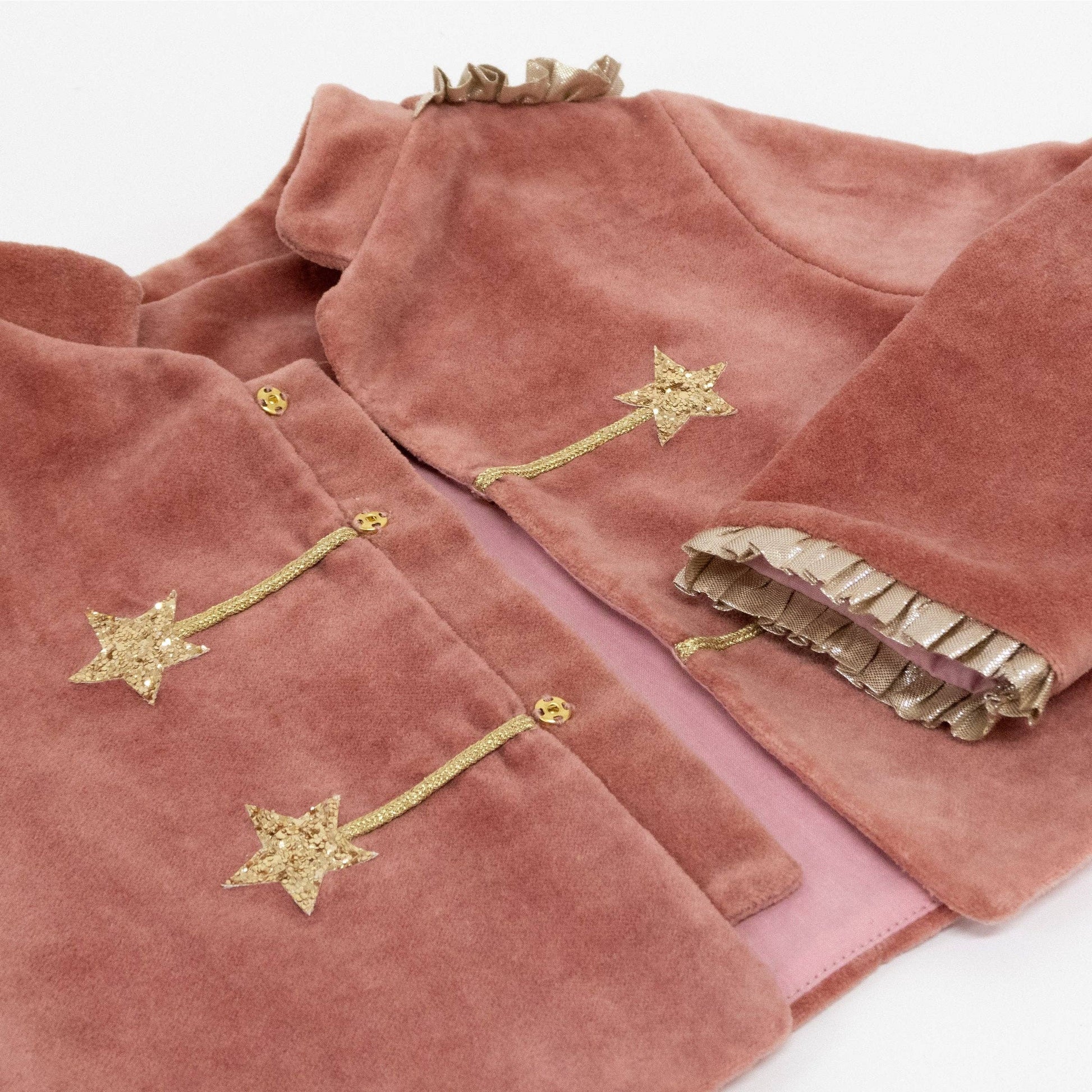 A dusty rose velvet jacket with gold embroidered star details and a gold ruffled trim, shown on a clean white background.