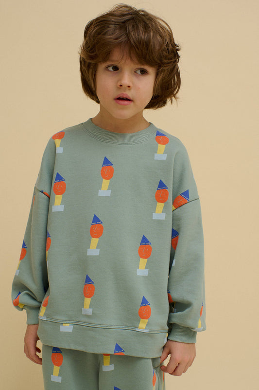Child wearing a green sweatshirt with colorful pattern on a beige background