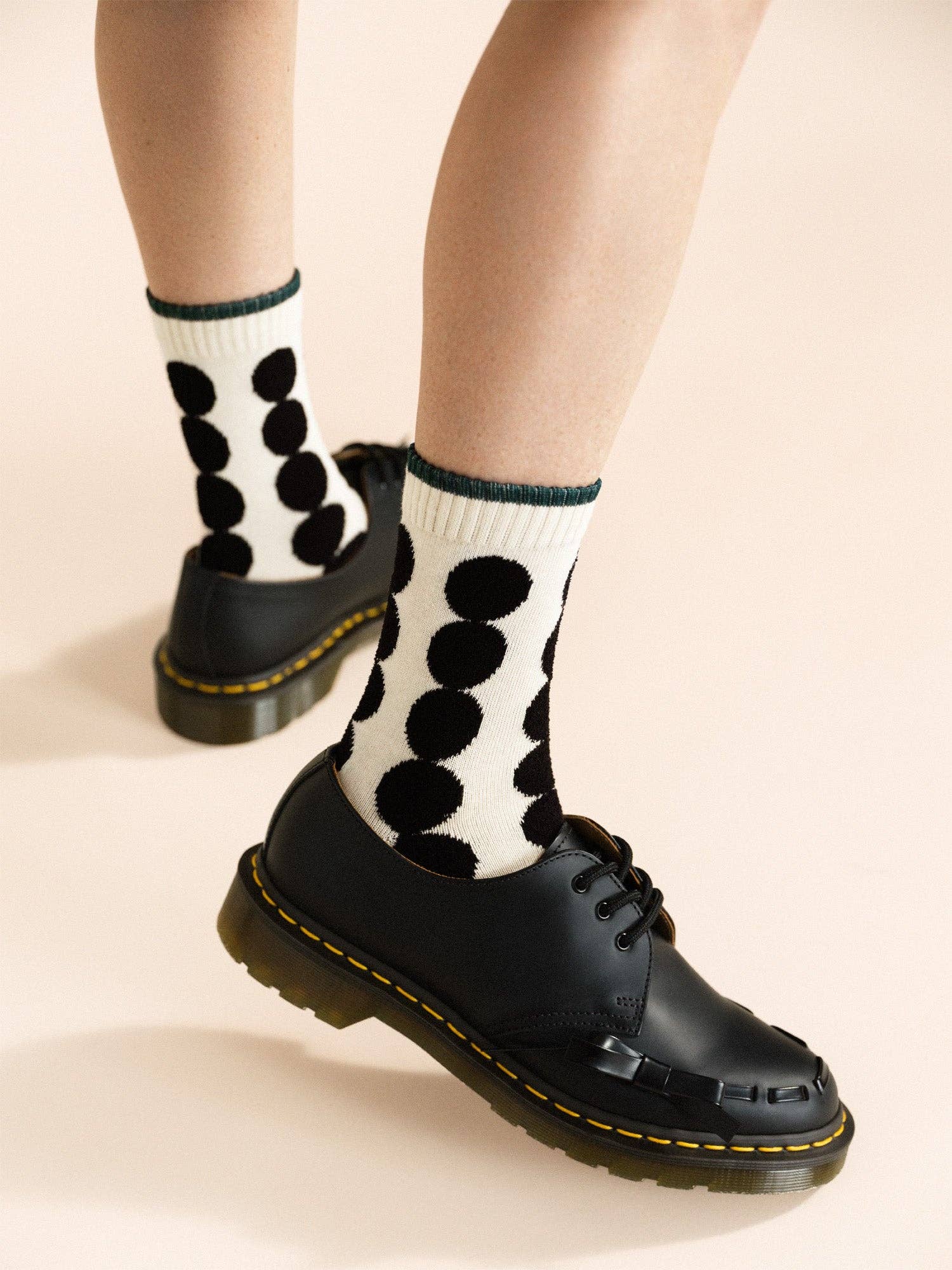 Black polka dot socks worn with black shoes on a beige background