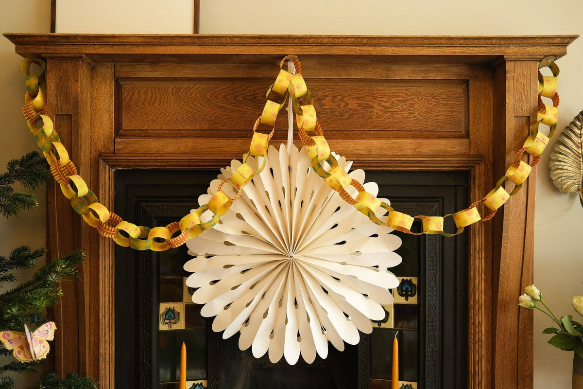 Yellow and green paper chain draped across a wooden fireplace above a white paper rosette.