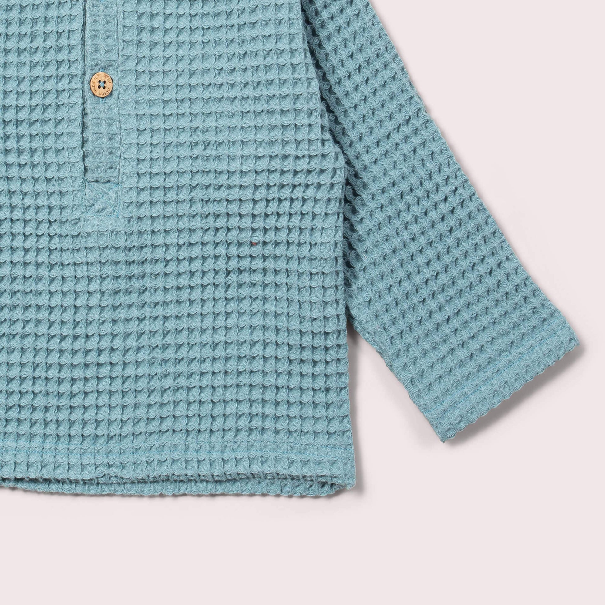 Teal textured shirt on a light pink background