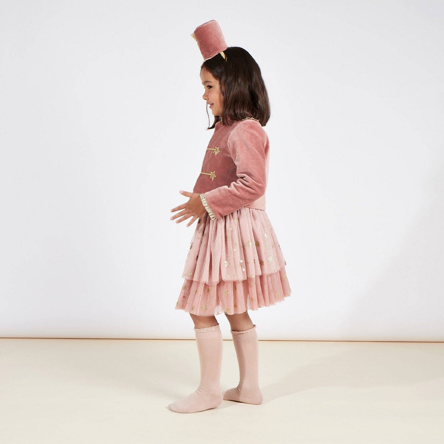 Young girl wearing a pink drummer costume with a white background