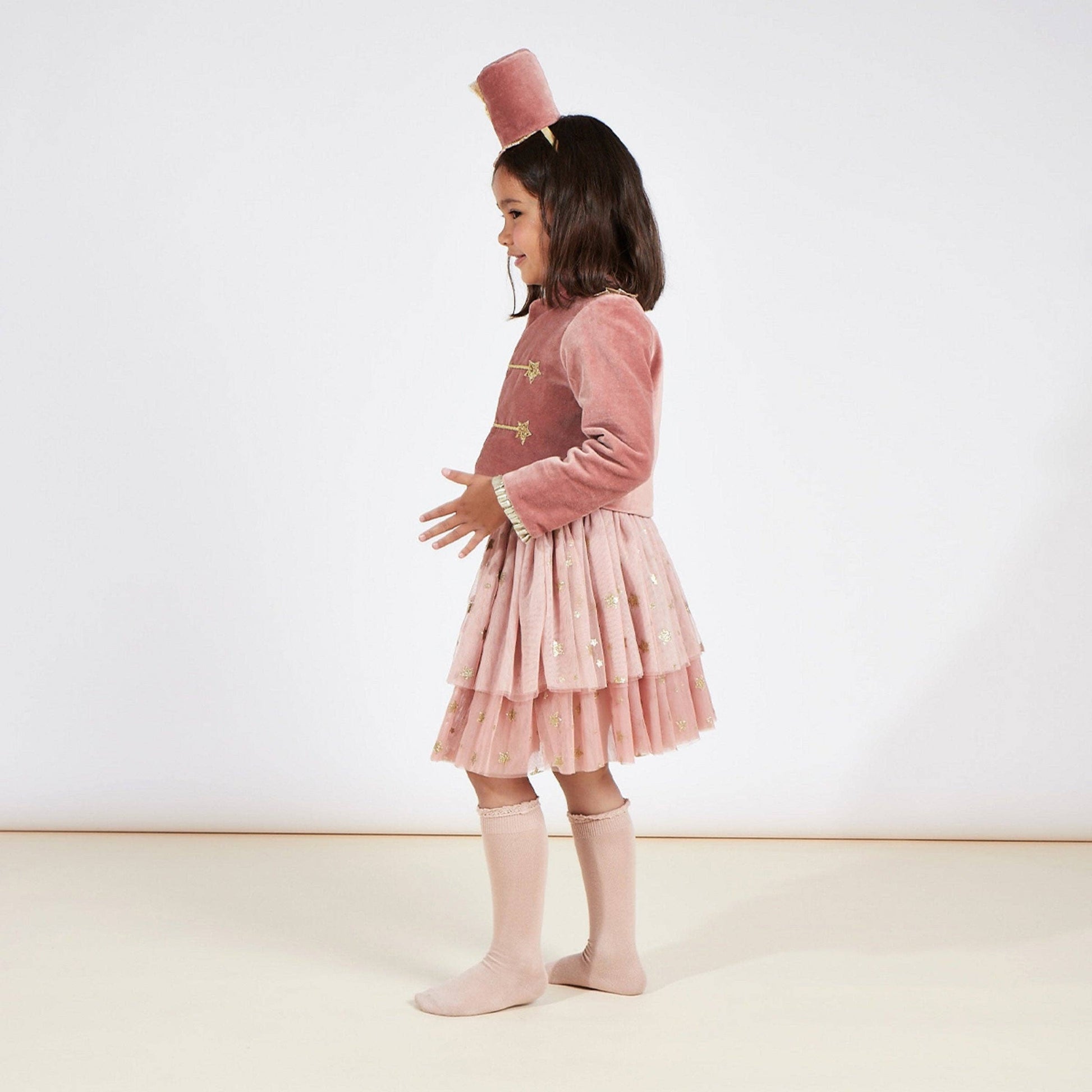Young girl wearing a pink drummer costume with a white background