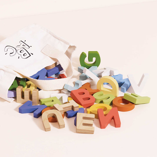 Colorful wooden letters scattered on a white surface with a white cloth.