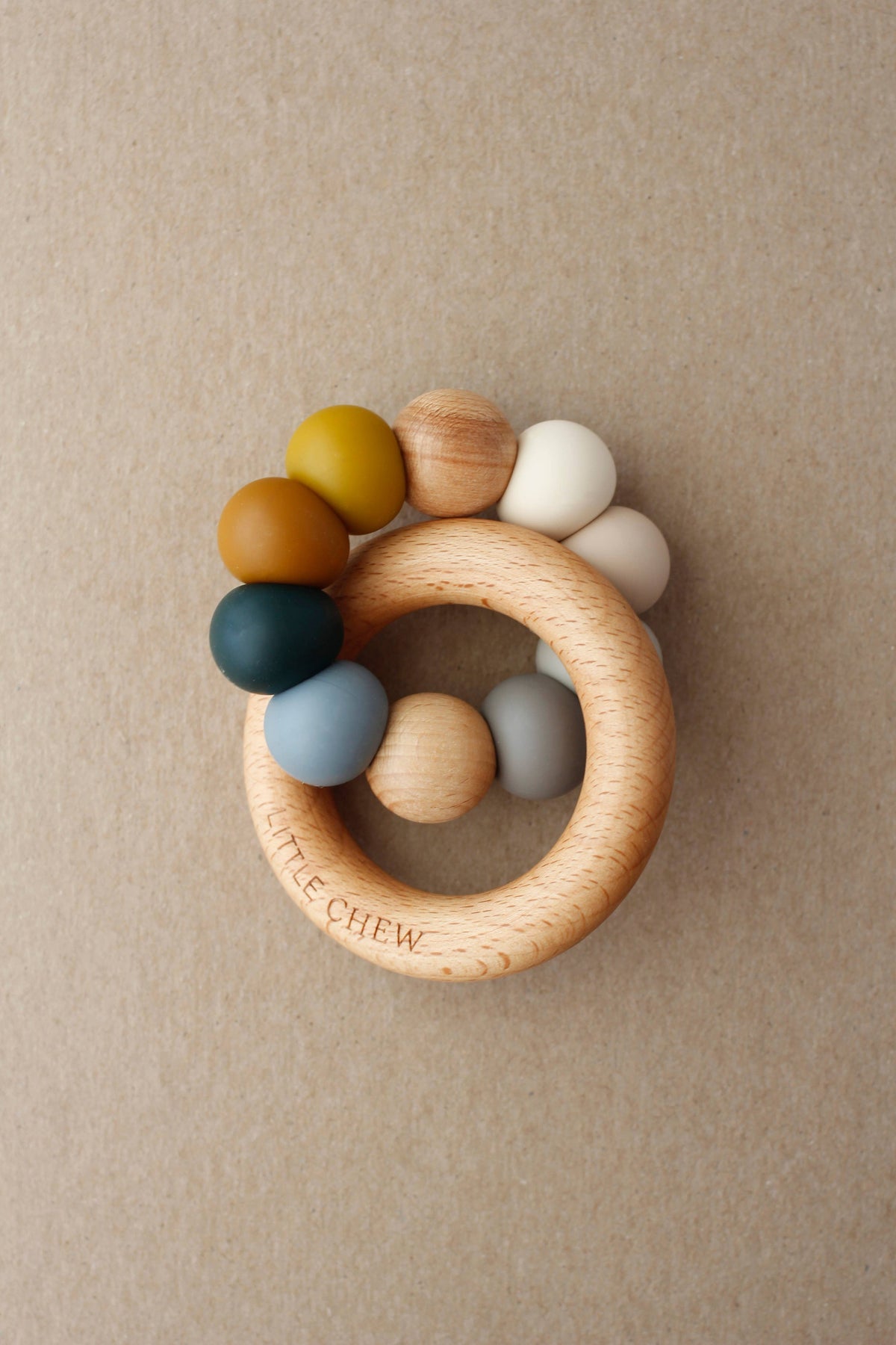 Wooden teething ring with colorful beads on a beige background