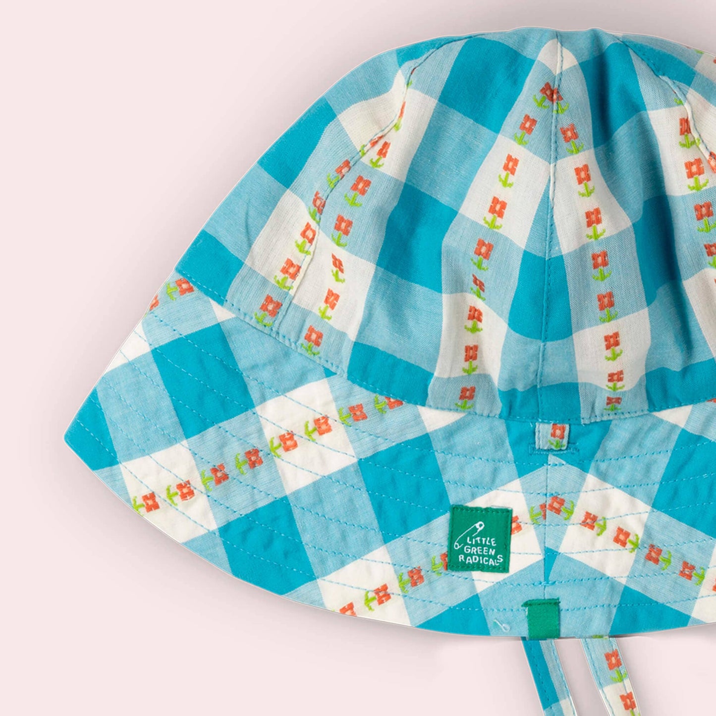 Children's raincoat with blue and white checkered pattern on a light pink background