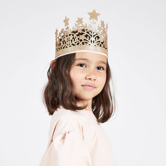 Young girl wearing a gold star-patterned crown on a white background