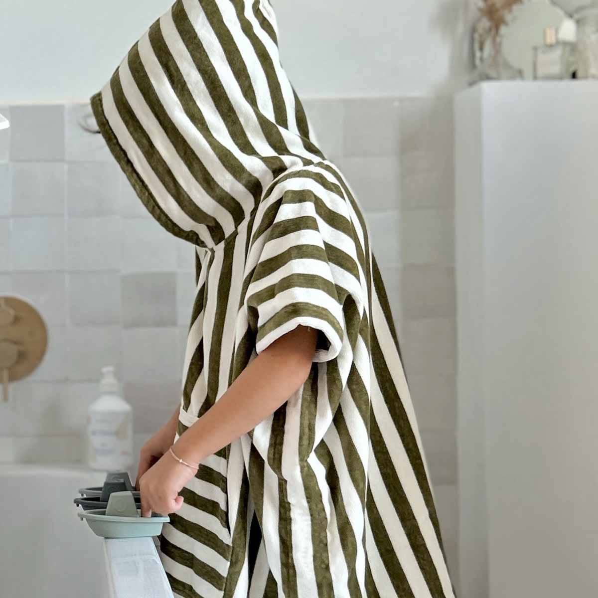 Person wrapped in a green and white striped towel in a bathroom.