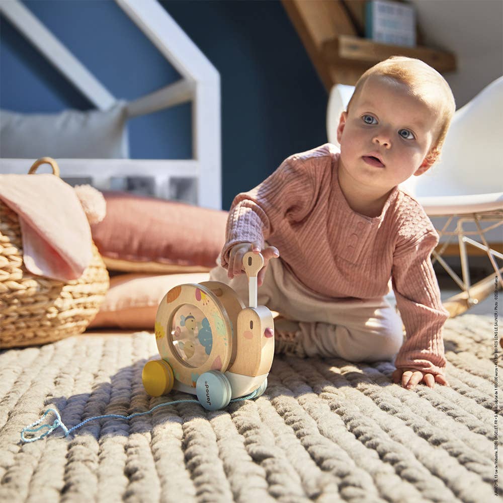 Baby playing with a wooden toy on a textured rug